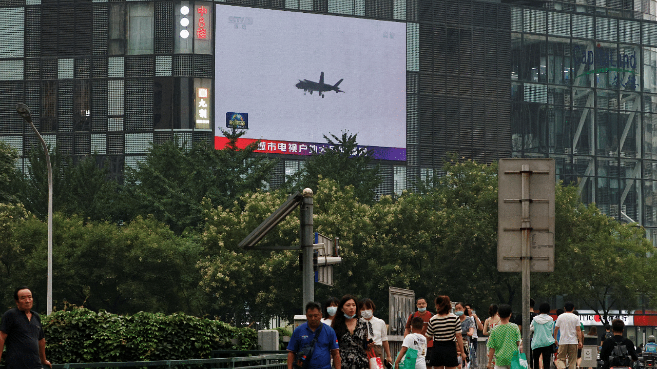 Pedestrians walk past a giant screen broadcasting news report on Chinese People's Liberation Army's (PLA) military exercises around Taiwan, in Beijing. Credit: Reuters Photo
