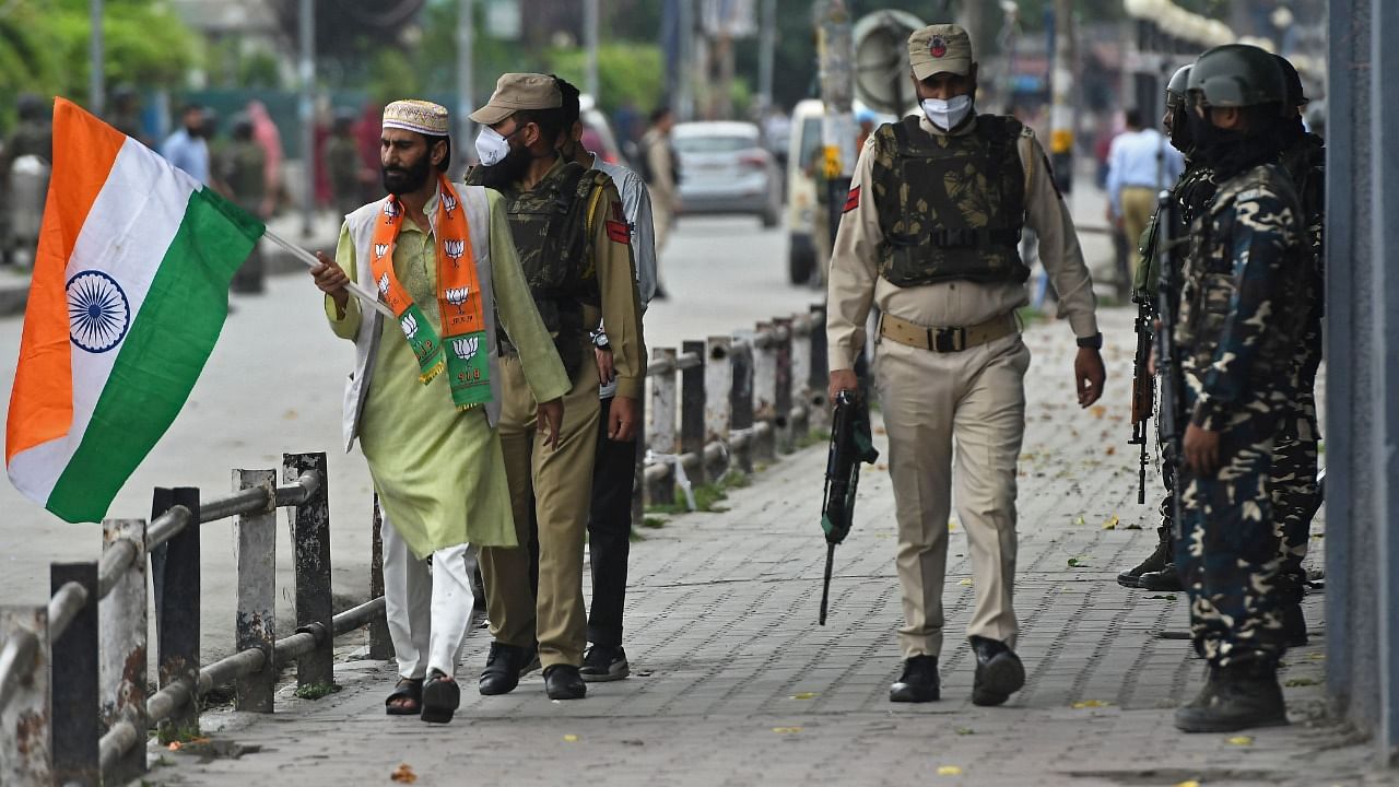 A supporter of the Bharatiya Janata Party (BJP) carries India's national flag as he walks to attend the Tiranga bikers rally at the clock tower in Lal Chowk. Credit: AFP Photo