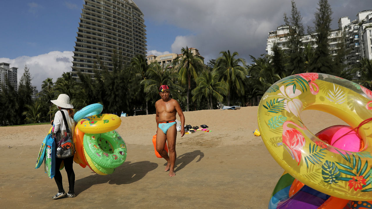 Vendors selling swimming accessories walk on Sanya Bay beach in Sanya, Hainan province, China November 26, 2020. Credit: Reuters File Photo 