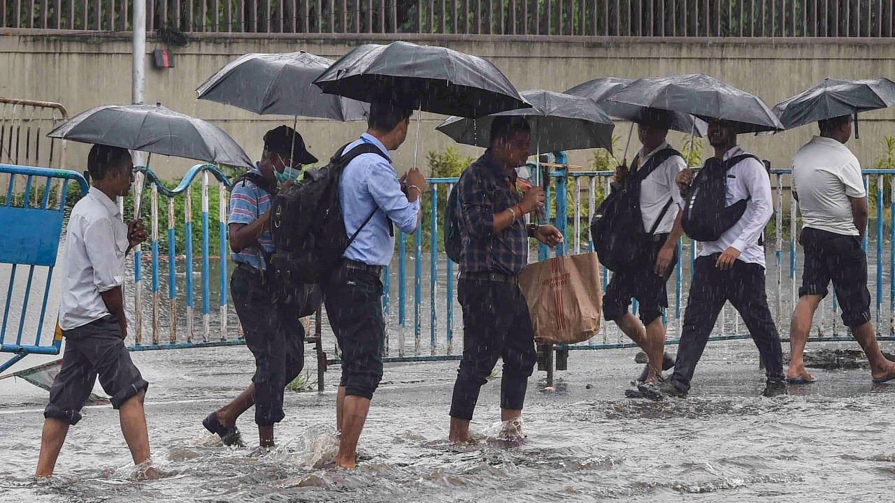 People walk under umbrellas to shield themselves from the monsoon rain, in Kolkata, Tuesday, August 2, 2022. Credit: PTI Photo