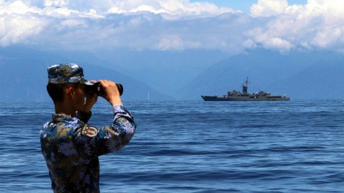 In this photo provided by China's Xinhua News Agency, a People's Liberation Army member looks through binoculars during military exercises as Taiwanese frigate Lan Yang is seen at the rear, on Friday, Aug. 5, 2022. Credit: AP/PTI Photo
