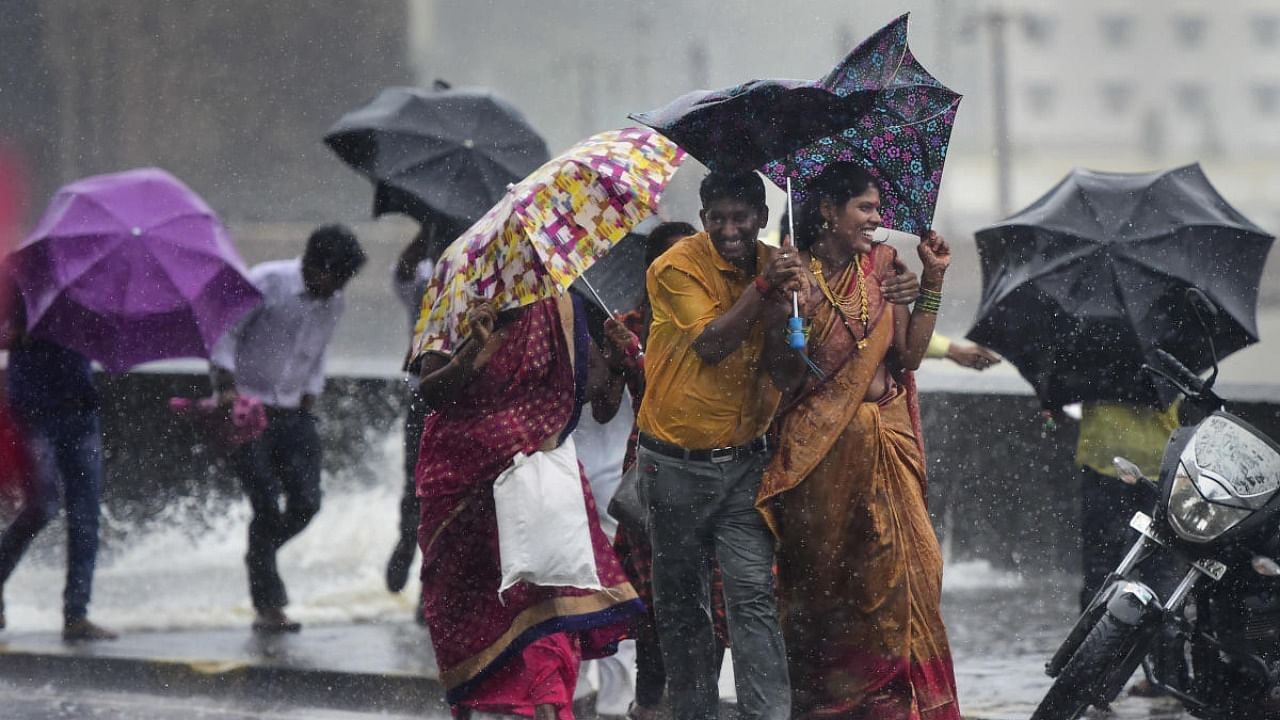 People try to protect themselves from rain at Gateway of India in Mumbai, Wednesday, July 14, 2022. Credit: PTI Photo