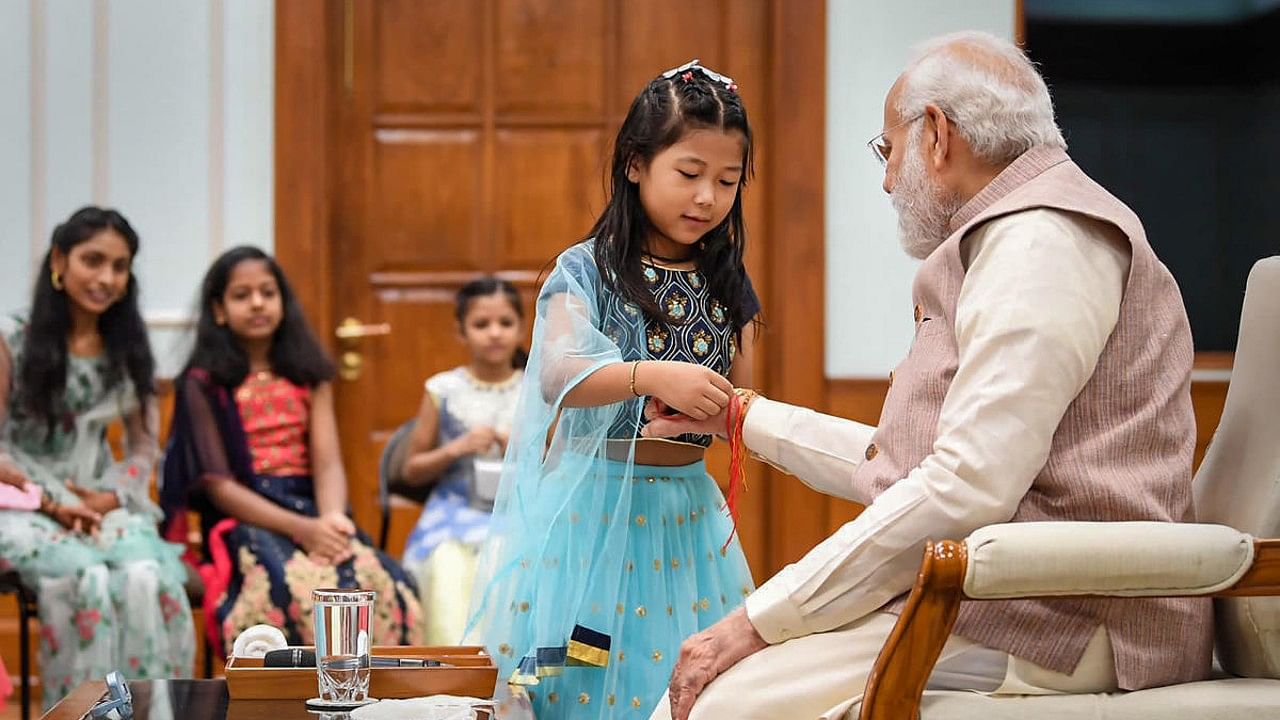 A girl ties 'rakhi' on the wrist of Prime Minister Narendra Modi during Raksha Bandhan celebrations, in New Delhi. Credit: PTI Photo