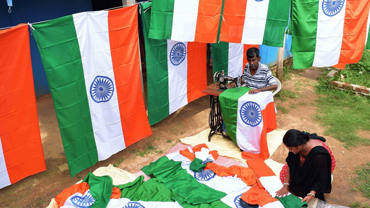 A tailor makes tricolor flags as a woman folds them at their workshop for the 'Har Ghar Tiranga'. Credit: IANS Photo