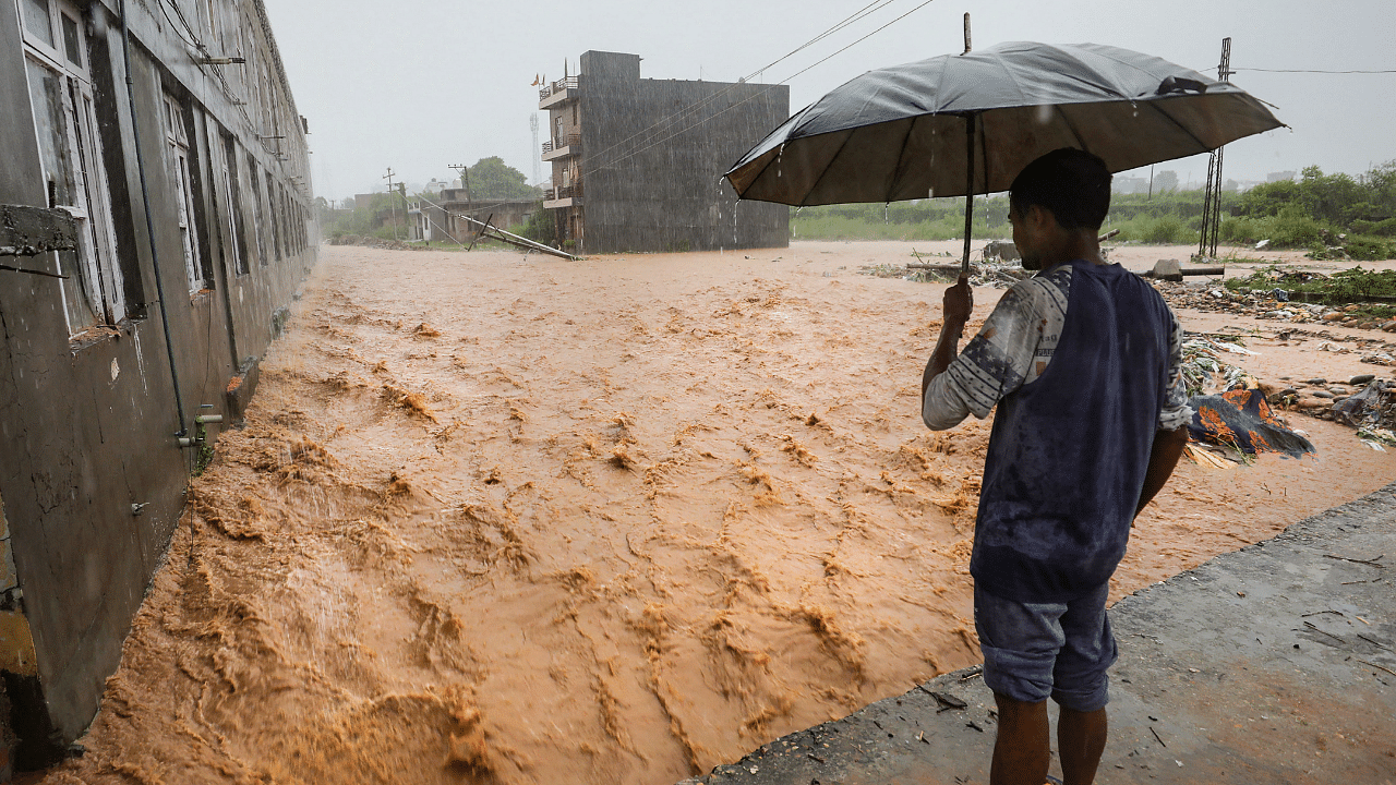 A man stands on an elevated ground during flash floods triggered by heavy monsoon rains, on the outskirts of Jammu. Credit: PTI Photo
