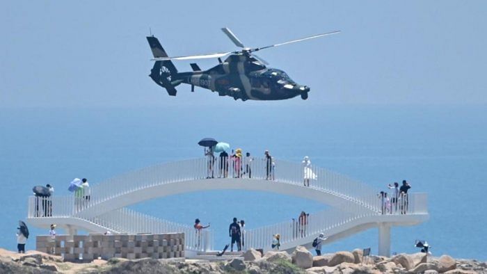 Tourists look on as a Chinese military helicopter flies past Pingtan island, one of mainland China's closest point from Taiwan. Credit: AFP Photo