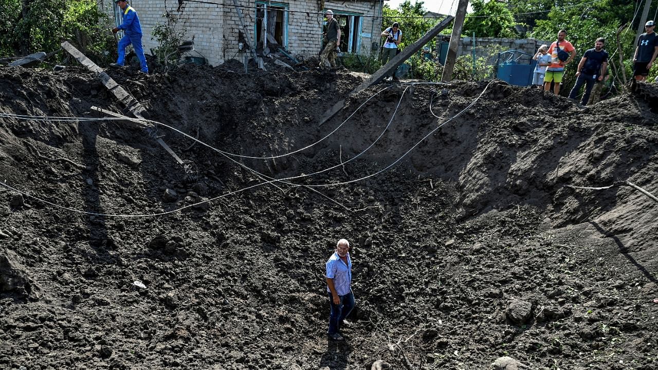 A man stands inside a crater left by a Russian missile strike in the settlement of Kushuhum. Credit: Reuters Photo