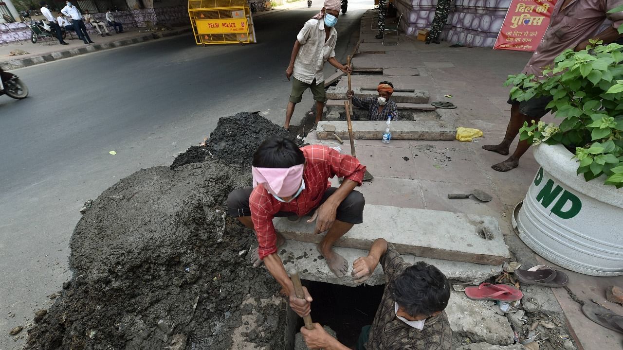 Workers clean a sewer manually. Credit: PTI Photo