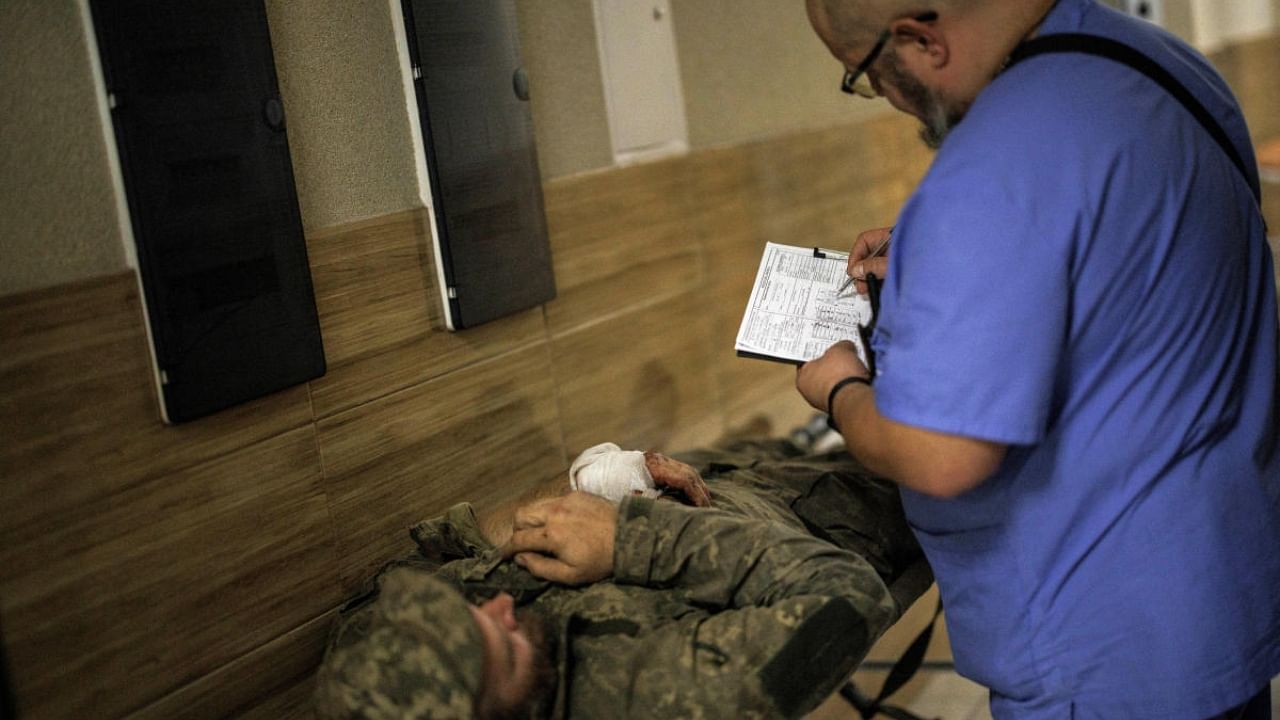 Volunteer doctor Andrii (last name not given) takes the medical history of a wounded Ukrainian soldier in a military hospital in Donetsk. Credit: Reuters Photo