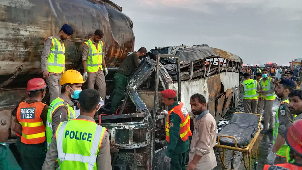 Rescue workers search for victims in the burnt wreckage of a bus following an overnight collision between a passenger bus and an oil tanker in Multan district on August 16, 2022. Credit: AFP Photo