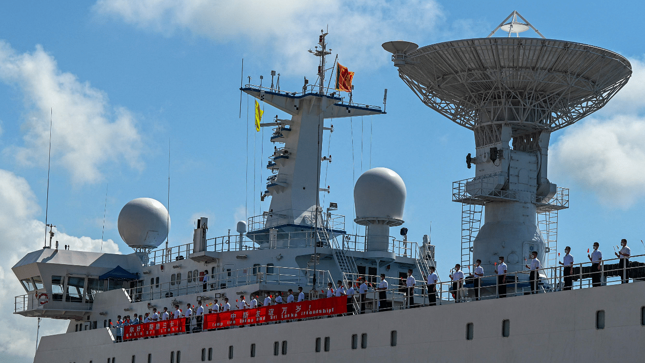 Crew aboard China's research vessel, the Yuan Wang 5, hold China's national flags upon arrival at Hambantota Port. Credit: AFP Photo