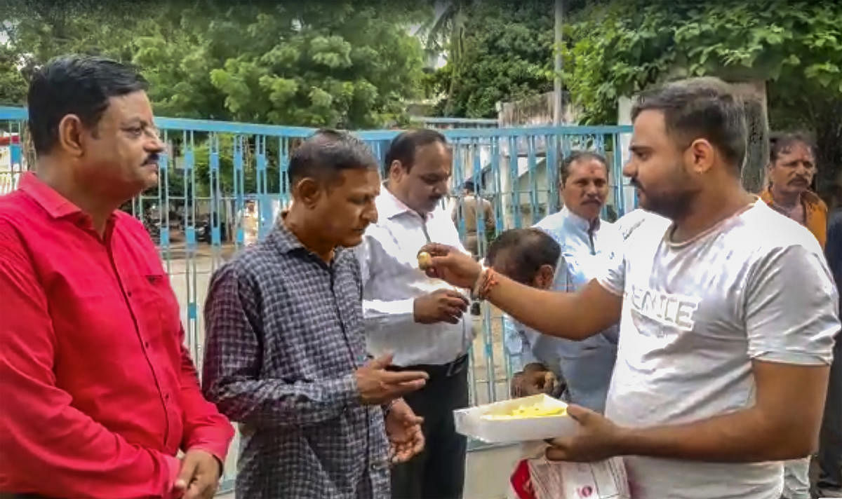 A man offers sweets to people convicted for rape and murder in the Bilkis Bano case, in Godhra. PTI