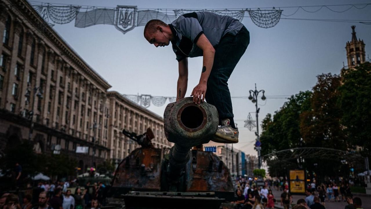 In this photograph taken on August 21, 2022 a man climbs on a destroyed Russian tank at Khreshchatyk street in Kyiv, that has been turned into an open-air military museum ahead of Ukraine's Independence Day on August 24, amid Russia's invasion of Ukraine. Credit: AFP Photo