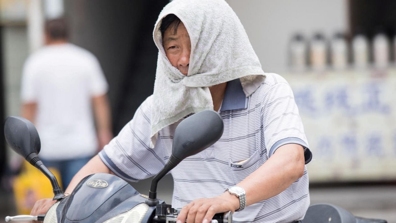 A man is seen with a towel tied around his head to escape hot weather as a heat wave hits Hangzhou, Zhejiang province, China. Credit: Reuters photo