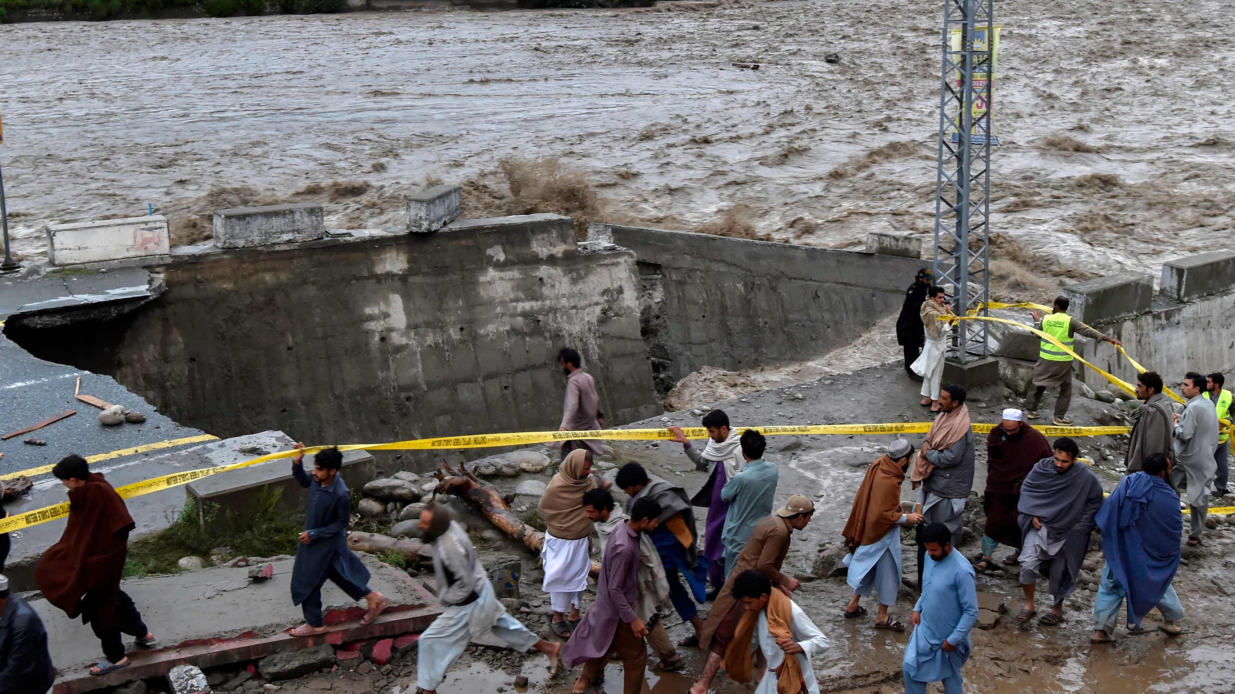People gather in front of a road damaged by flood waters following heavy monsoon rains in Madian area in Pakistan's northern Swat Valley on August 27. Credit: AFP Photo