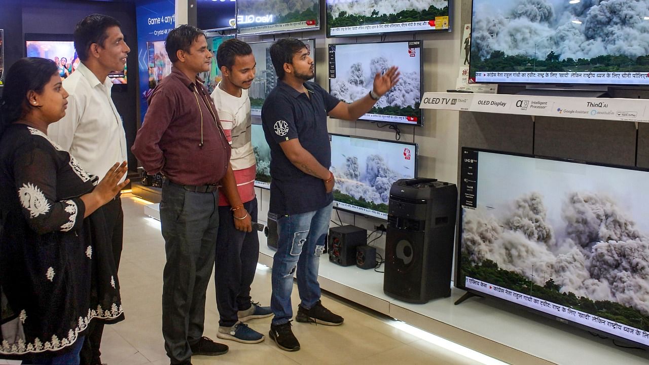 People watch a broadcast of the demolition of Supertech's twin towers in Noida, at an electronics store. Credit: PTI Photo