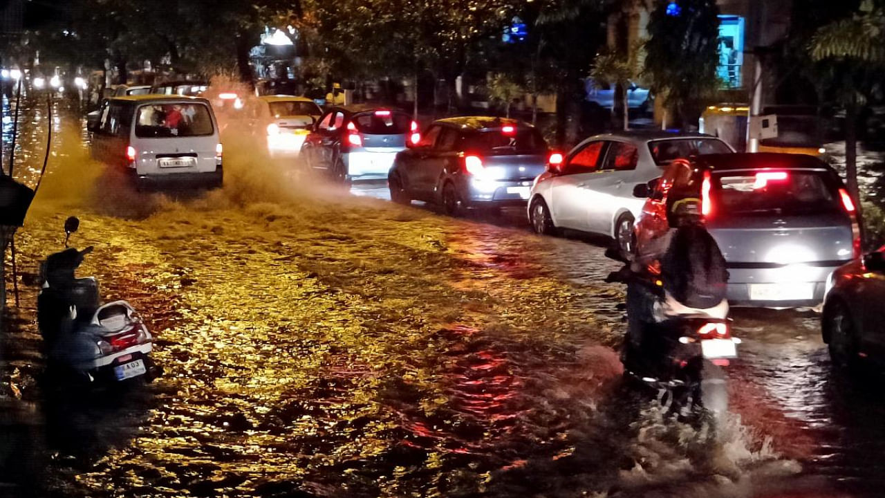 Cars travel along the waterlogged Mysuru Road. Credit: DH Photo