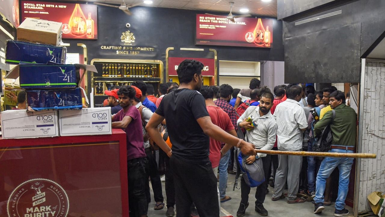 People buy liquor at a store at Azadpur area, in New Delhi, Wednesday, Aug 31, 2022. Delhi will revert to the old liquor policy regime from September 1, bringing an end to the new liquor policy, which has been marred by allegations of corruption. Credit: PTI Photo