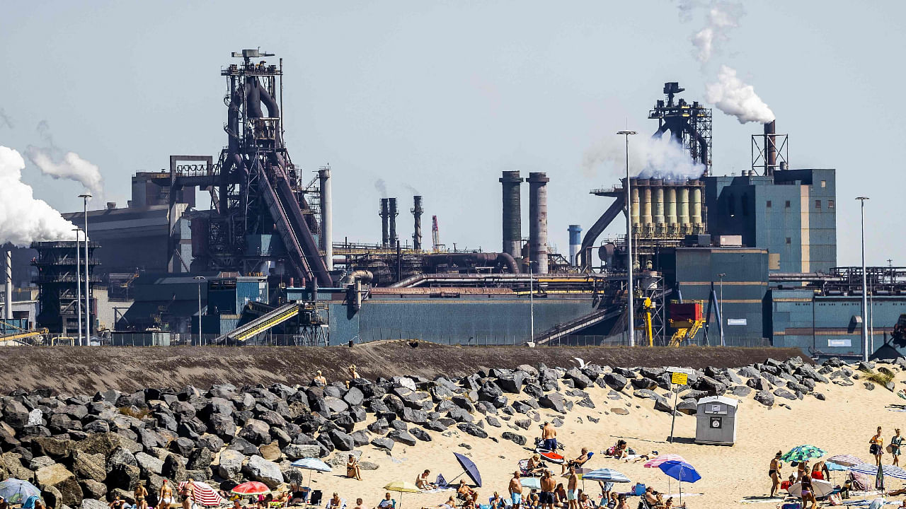 Beachgoers enjoy the sun on the Kleine Strand (the Small Beach), with the Velsen-Noord Tata Steel plant in the background, in IJmuiden, near Amsterdam on August 13, 2022. Credit: AFP Photo