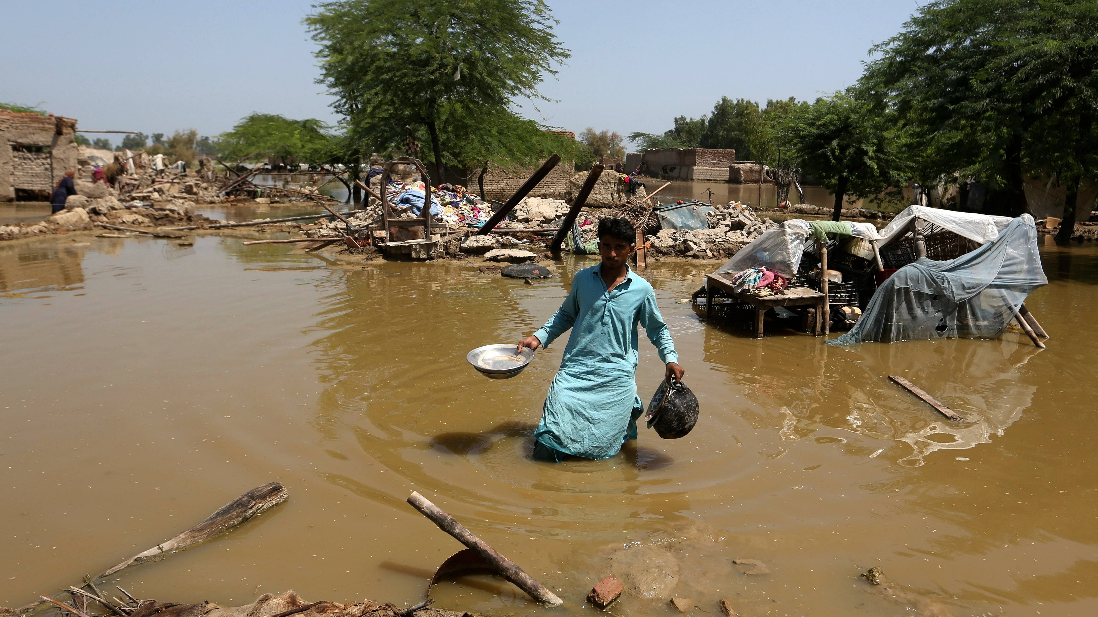 A man looks for salvageable belongings from his flooded home in the Shikarpur district of Sindh Province, Pakistan. Credit: AP/PTI Photo