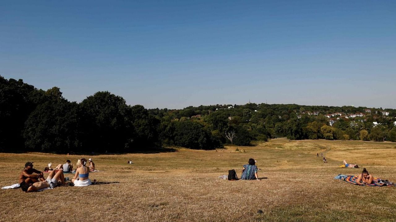 People sit on the dried grass at the Hampstead Heath park, in London. Credit: AFP Photo