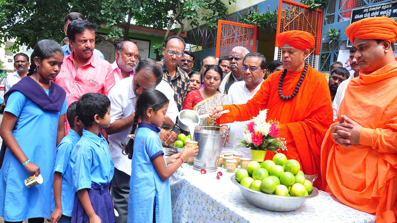 Shivamurthy Murugha Sharanaru distributes milk and fruit to children at a government school in Chitradurga, August 5, 2022. Credit: DH File Photo
