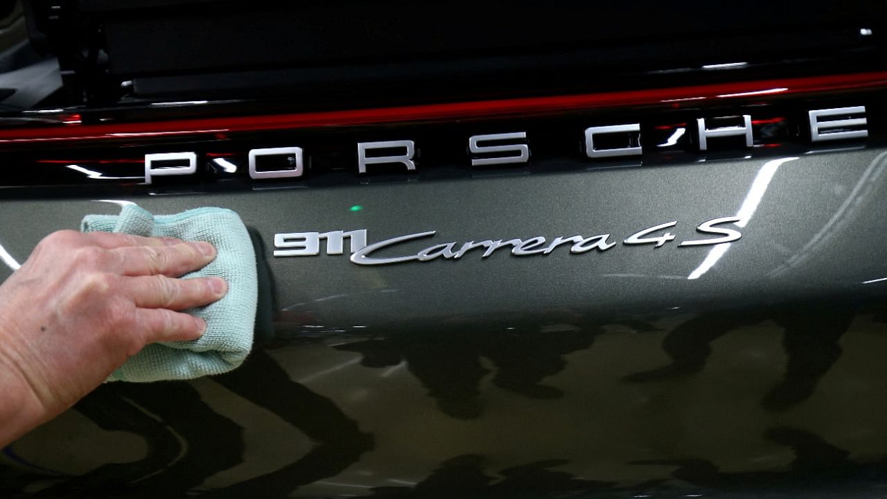 An employee of German car manufacturer Porsche fixes a Porsche 911 Carrera 4S label at the Porsche factory in Stuttgart-Zuffenhausen. Credit: Reuters Photo