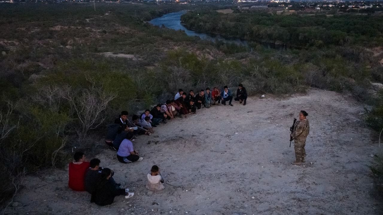 A member of the Texas Army National Guard stands near asylum-seeking migrants after they crossed the Rio Grande river into Roma, Texas, US on August 29.  Credit: Reuters Photo
