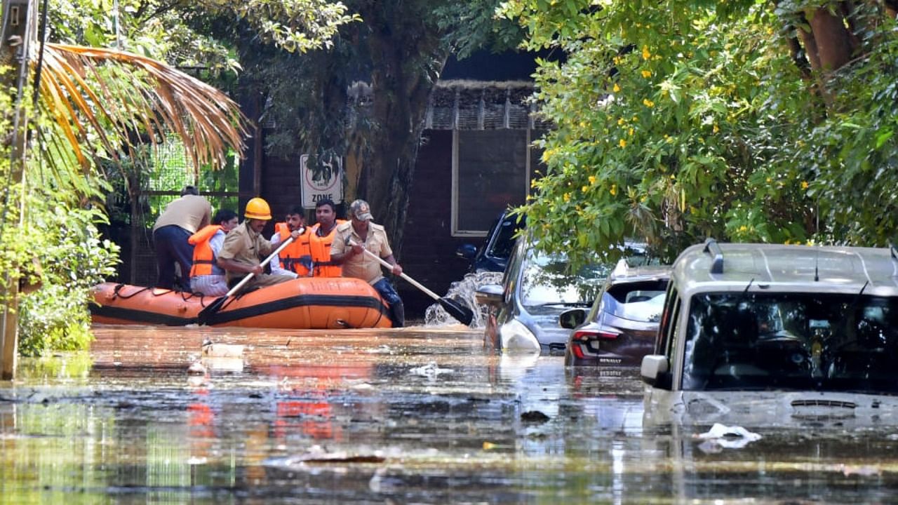 Members of a rescue team row their boat past submerged vehicles following torrential rains in Bengaluru. Credit: Reuters Photo