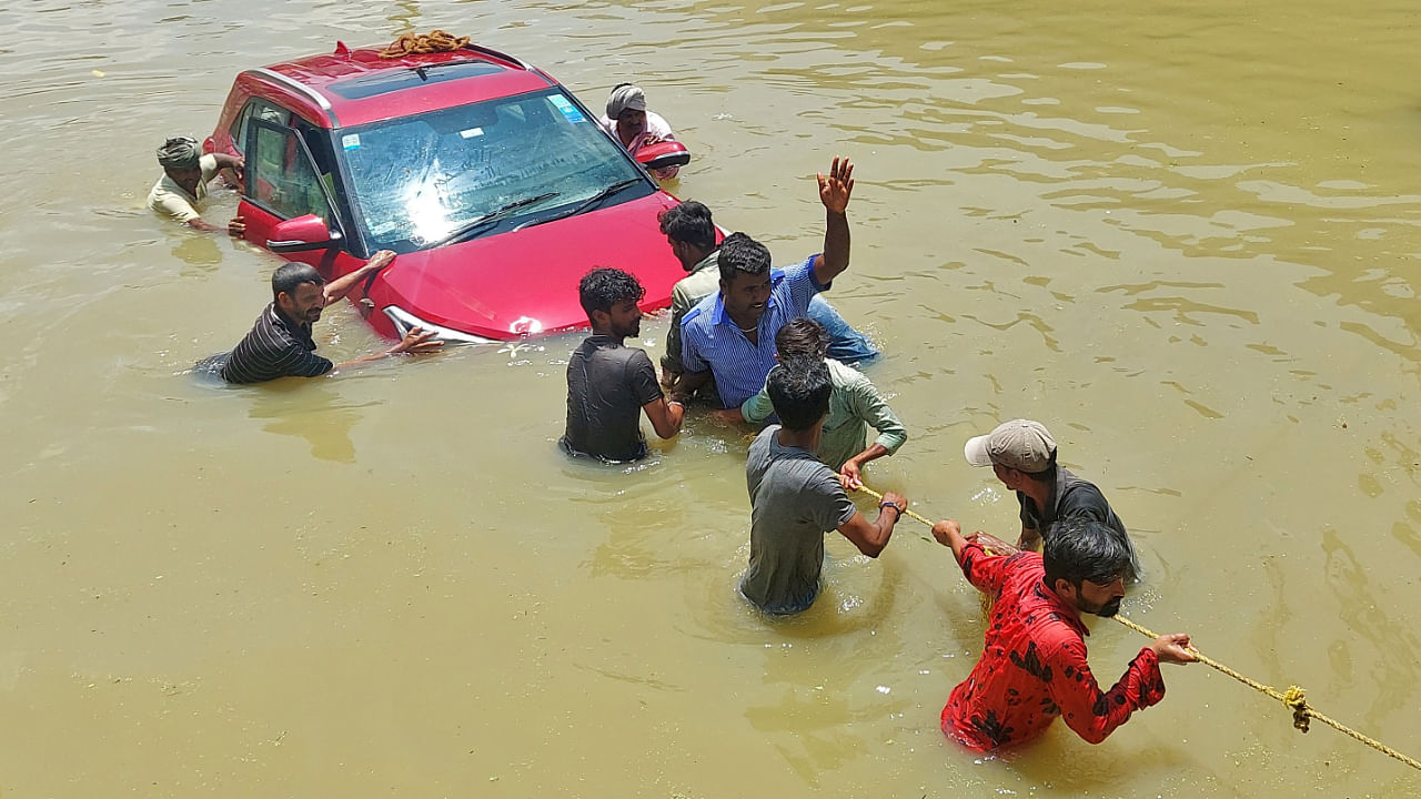 People pull a car through a water-logged road following torrential rains in Bengaluru, September 5, 2022. Credit: Reuters Photo