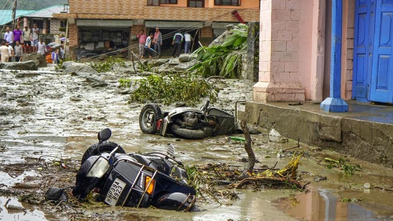 Two-wheelers lie partially submerged in mud on a road after flash floods triggered by a cloudburst at Khaniara, in Dharamshala, Friday, Sept. 2, 2022. Credit: PTI Photo