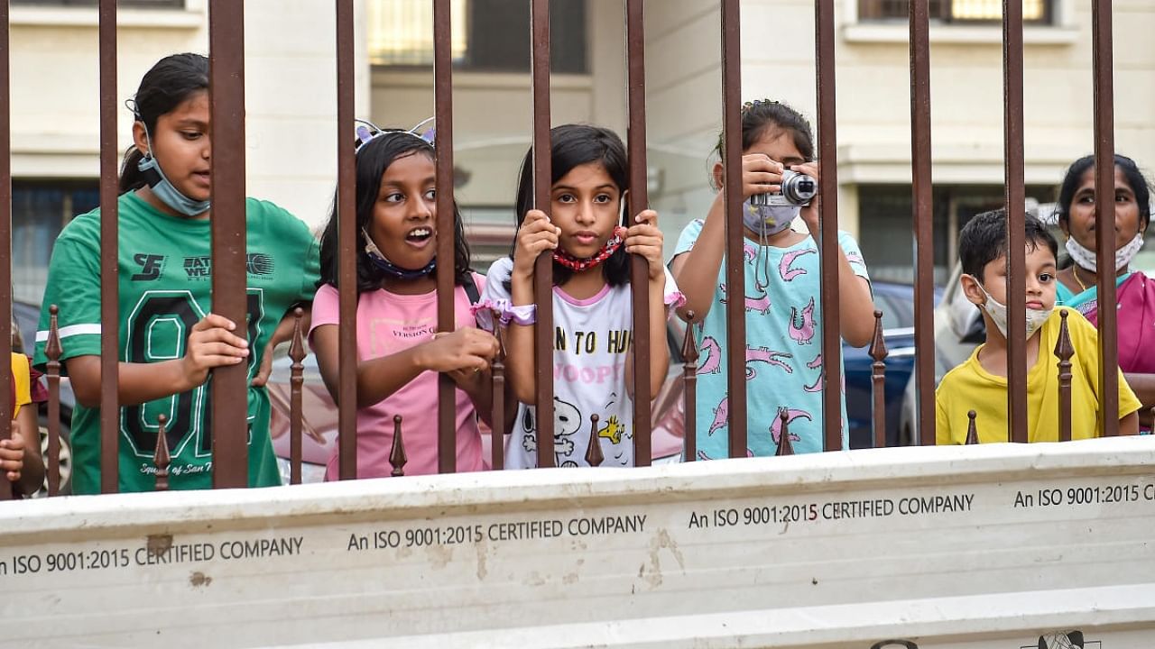 Children look at a waterlogged street from their residence after heavy monsoon rains, at Yemalur in Bengaluru, Tuesday, September 6, 2022. Credit: PTI Photo