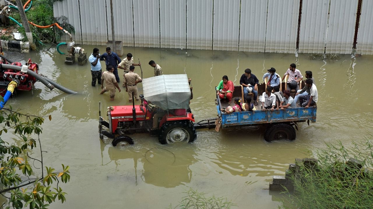 People commute in a tractor trolley through a water-logged neighbourhood following torrential rains in Bengaluru. Credit: Reuters photo