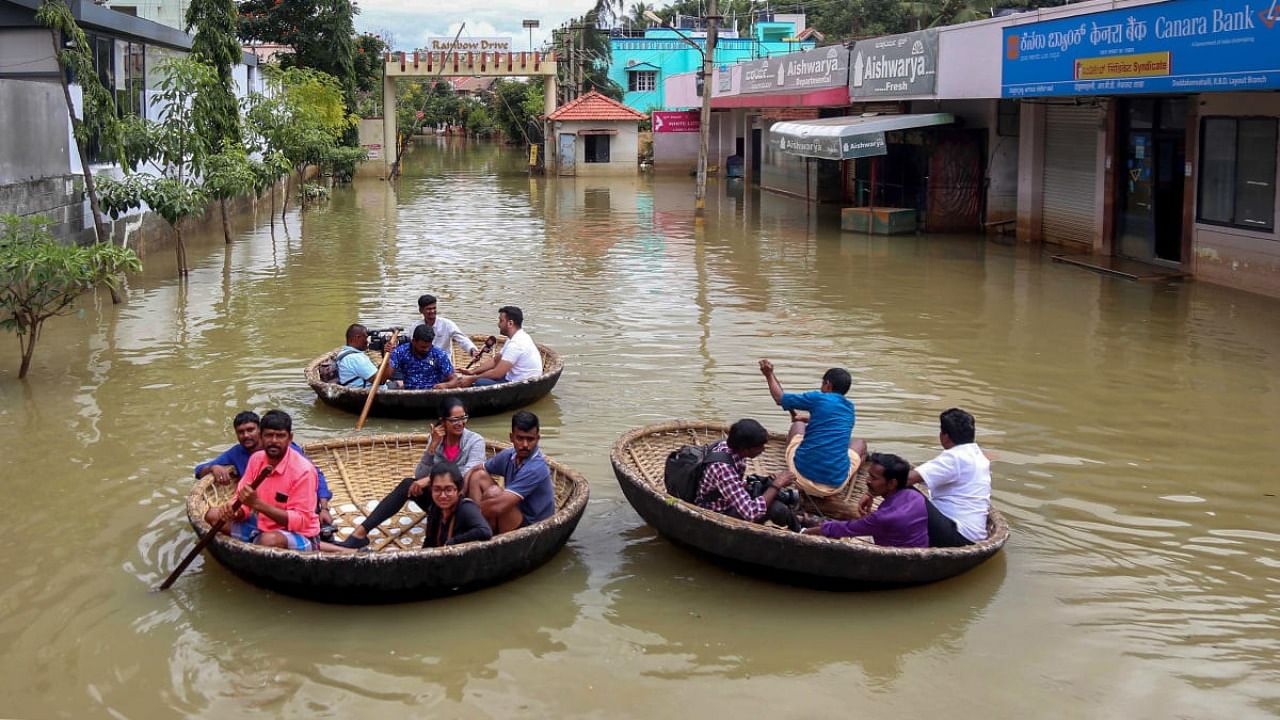 Residents of waterlogged Rainbow Drive Layout use coracles to commute after heavy monsoon rains, at Sarjapur in Bengaluru. Credit: PTI Photo