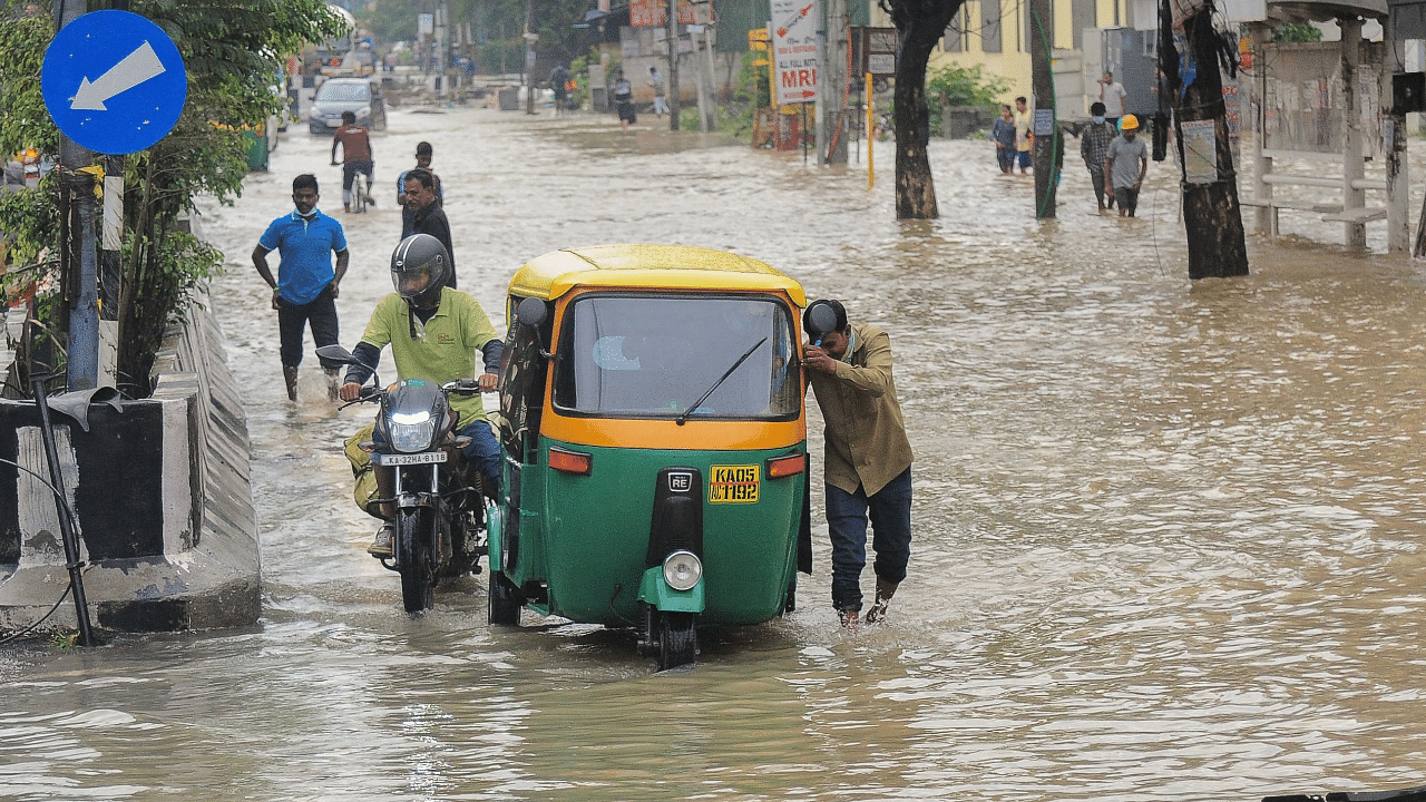 A drives pushes his auto-rickshaw along a waterlogged street after heavy rains in a Bangalore. Credit: AFP Photo