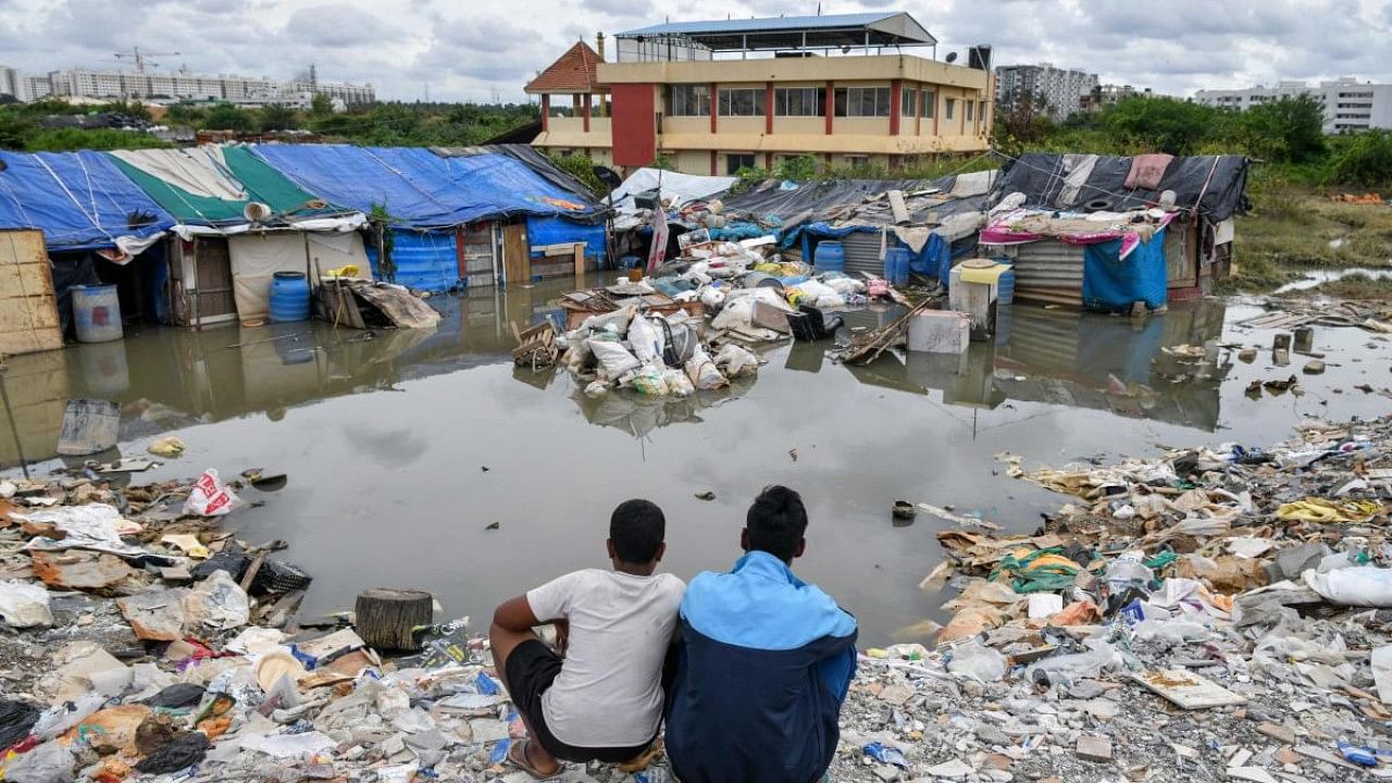 People living in a slum sit near to their waterlogged dwelling after heavy rains in Bangalore. Credit: AFP Photo