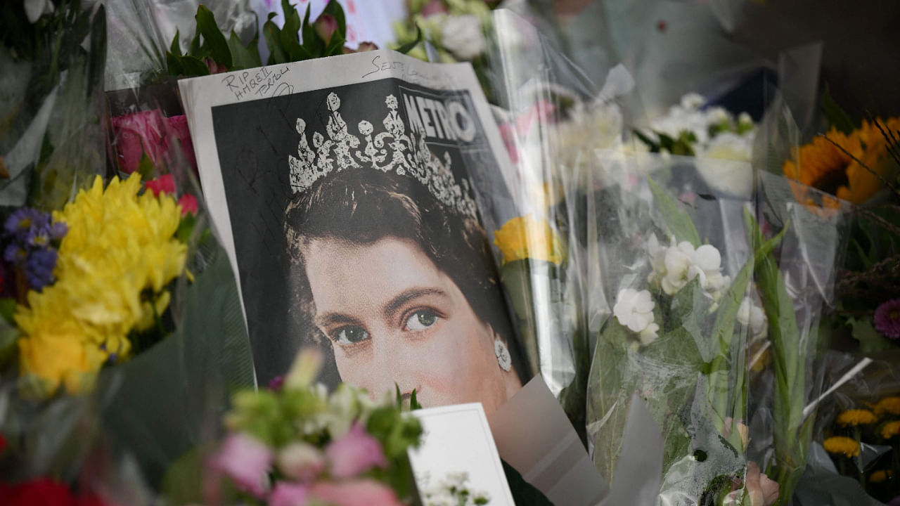 The front page of a news paper and flowers are pictured outside of Buckingham Palace in London on September 9, 2022, a day after Queen Elizabeth II died at the age of 96. Credit: AFP Photo