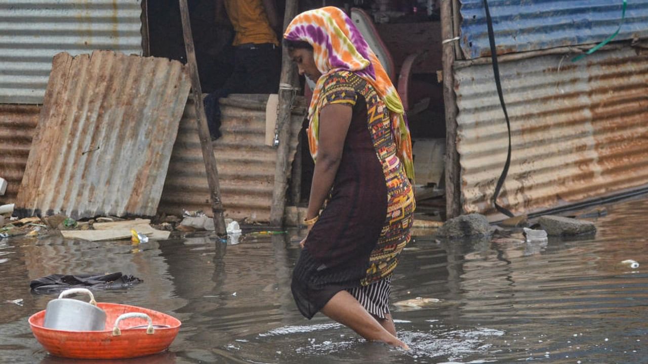 A woman walks through a waterlogged Munnekolala slum area due to overflowing of the Varthur lake, following heavy monsoon rains in Bengaluru, Thursday, Sep. 8, 2022. Credit: PTI Photo