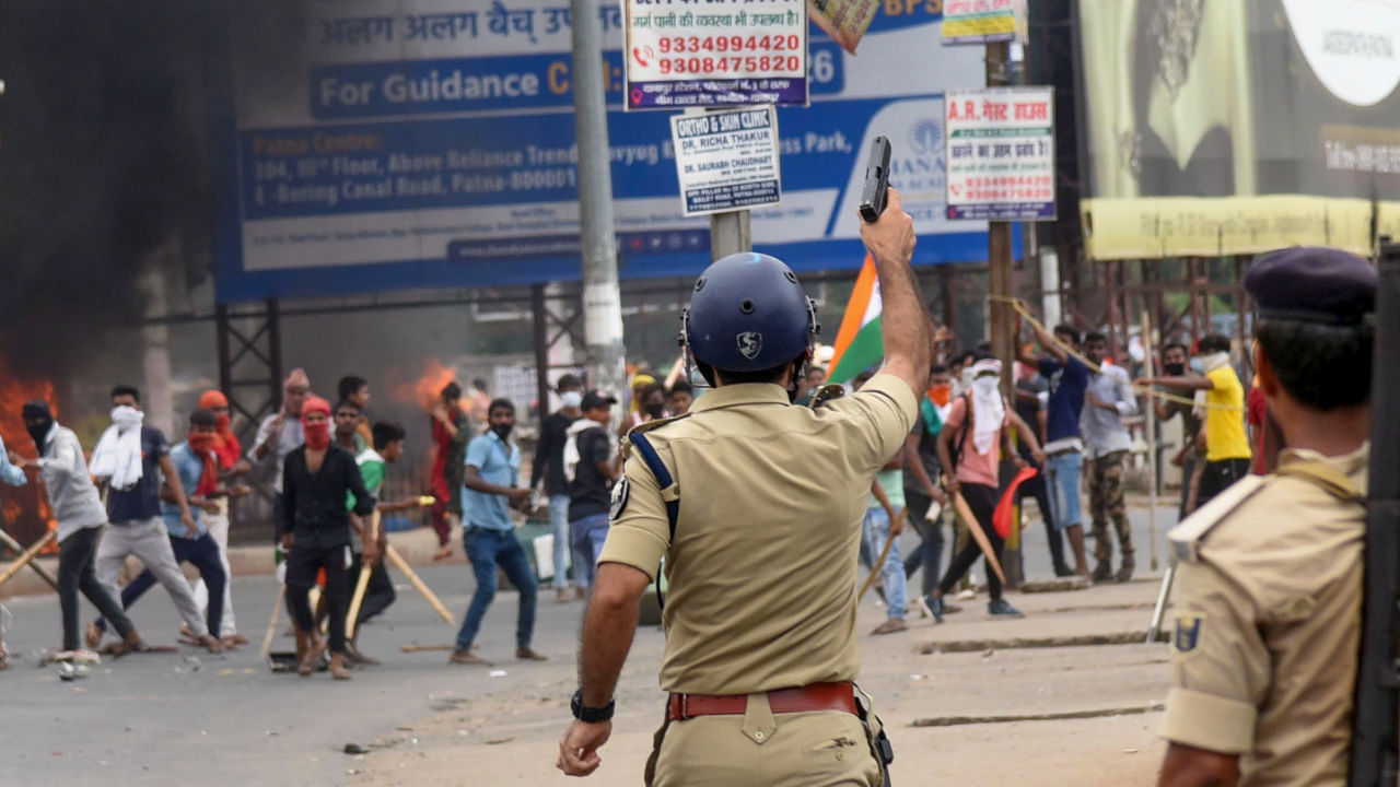 A policeman aims to fire in the air to disperse people protesting against Centre's 'Agnipath' scheme, in Danapur near Patna, June 17, 2022. Credit: PTI File Photo