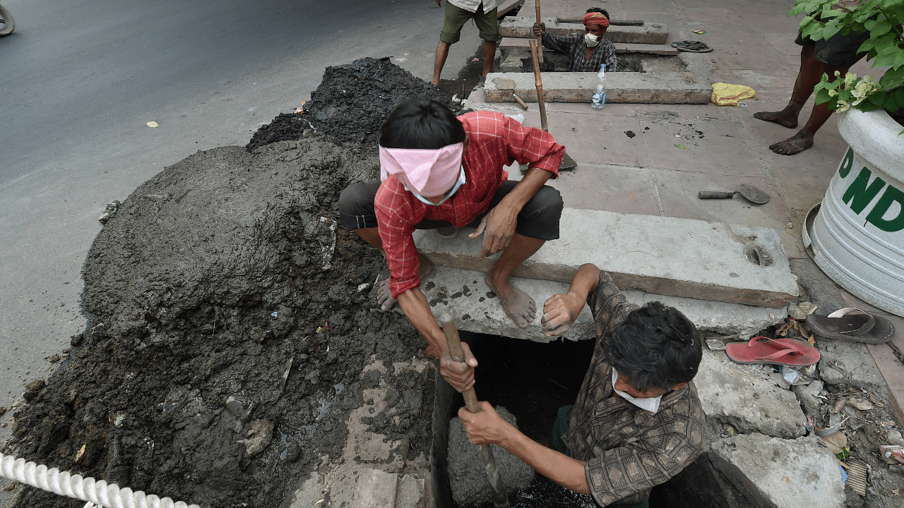 Workers clean a sewer manually during Unlock 4, in New Delhi. Credit: PTI Photo
