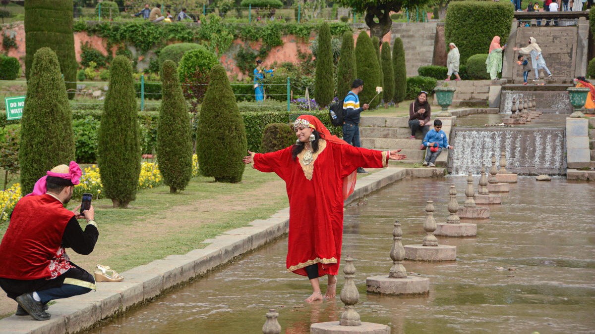 Tourists click photos during their visit to Nishat Bagh Mughal garden, on the banks of Dal Lake in Srinagar. Credit: PTI Photo