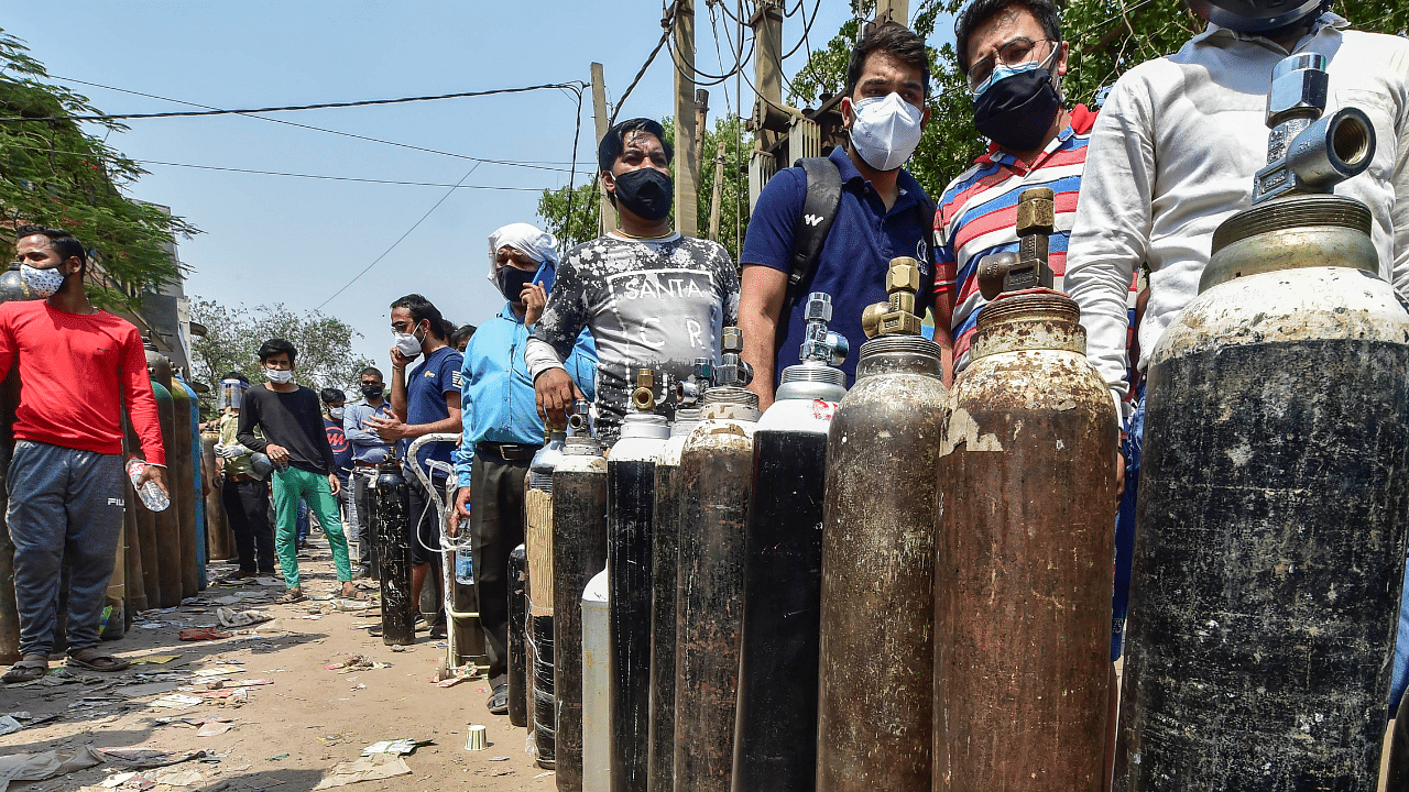 In this file image dated April 27, 2021, family members of COVID-19 patients wait outside an oxygen-filling centre to refill their empty cylinders. Credit: PTI Photo