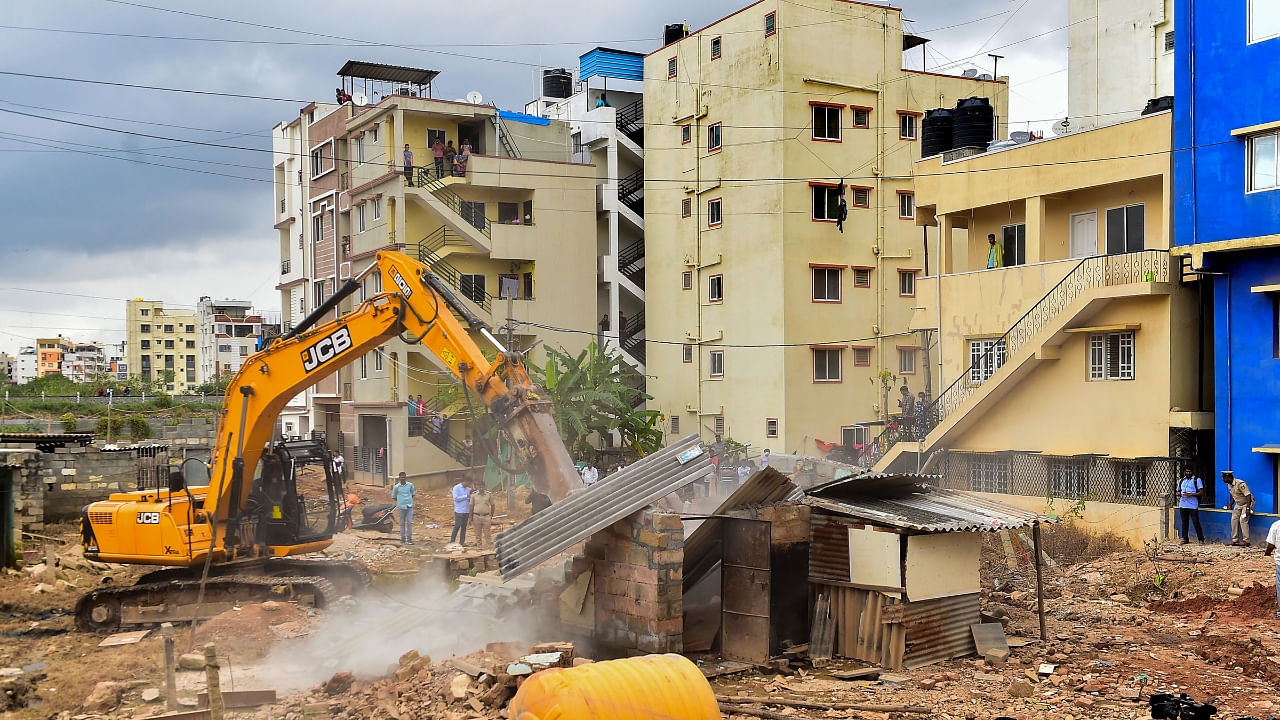 A BBMP bulldozer demolishes an illegal structure built on storm-water drain in Munnekolala area, which was recently flooded due to heavy monsoon rains, in Bengaluru, Tuesday, Sep. 13, 2022. Credit: PTI Photo