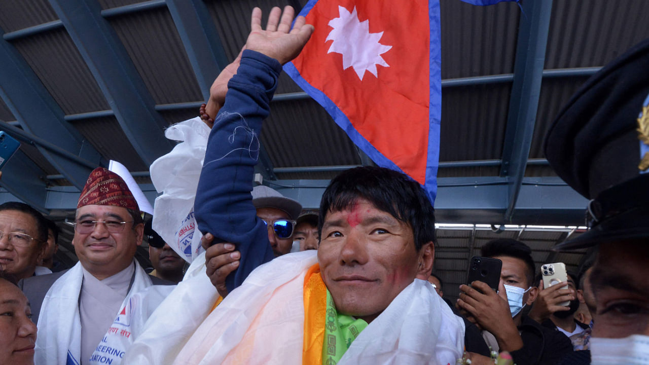Nepali mountaineer Sanu Sherpa (C) is welcomed upon arriving at Tribhuvan airport after becoming the first climber to summit all the world's 14 peaks above 8000 meters (26,247 ft) for the second time, in Kathmandu on August 20, 2022. Credit: AFP File Photo