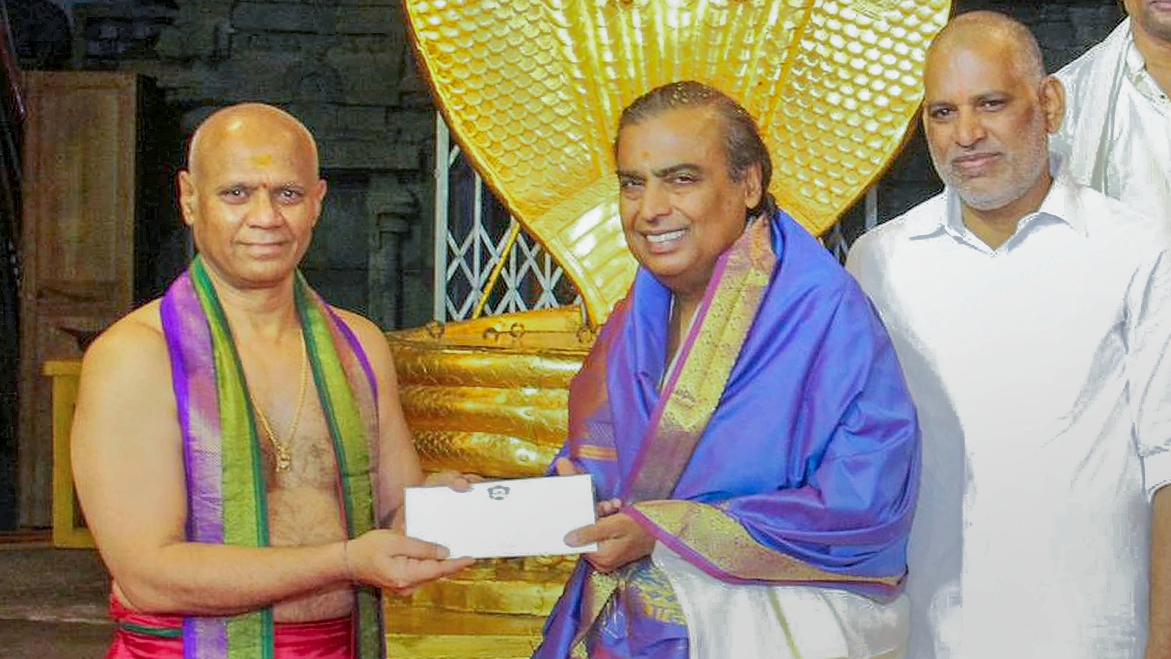 Mukesh Ambani hands over a cheque for Rs 1.5 crore to TTD Additional Executive Officer. Credit: PTI Photo