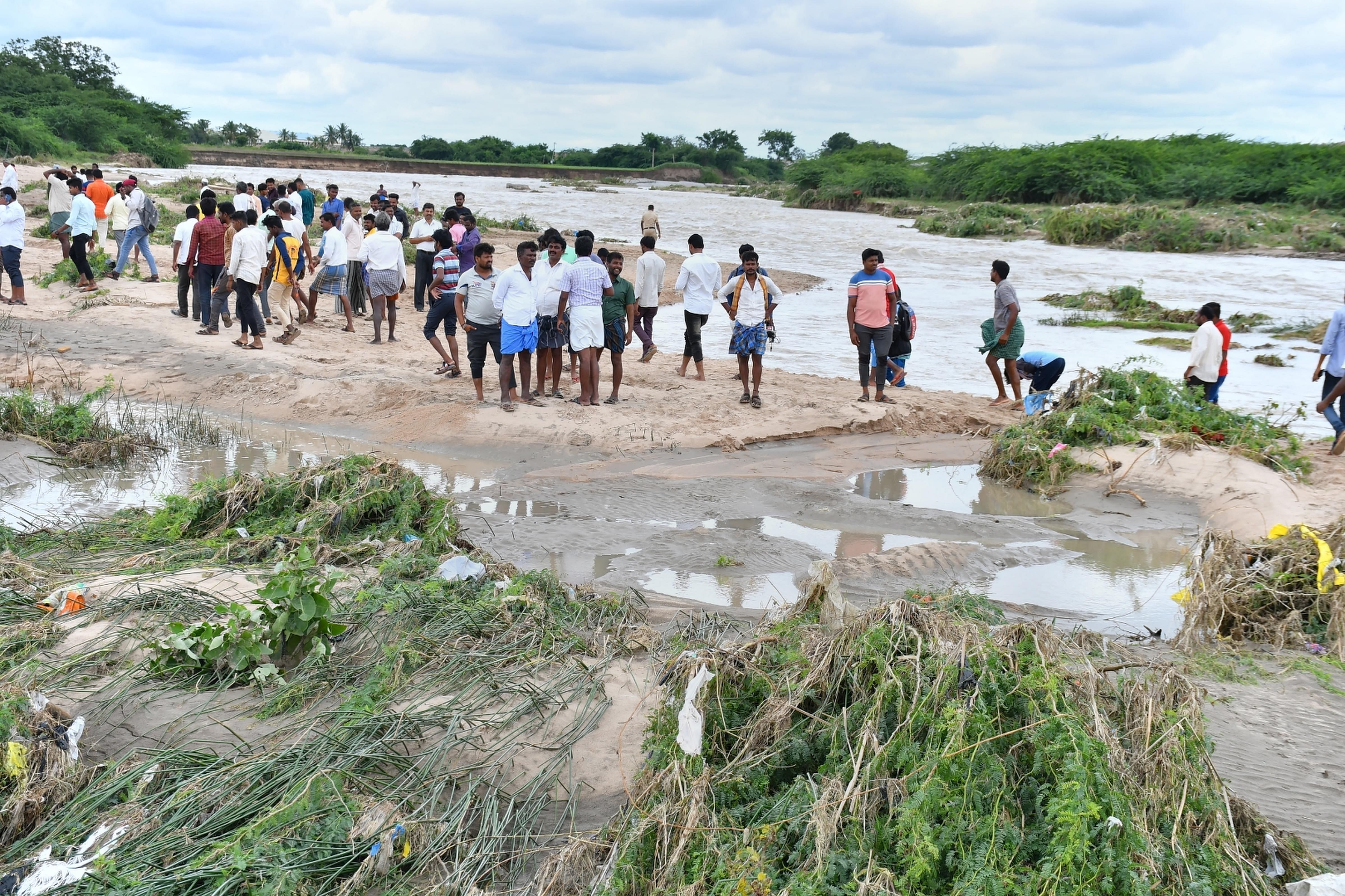 Villagers stand on an elevated ground as Fire and Emergency Department team rescue farmers stranded in a flood-affected area near Koluru village in Koppal. Credit: PTI Photo