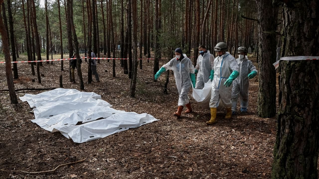 Members of Ukrainian Emergency Service carry a body as they work at a place of mass burial during an exhumation, as Russia's attack on Ukraine continues. Credit: Reuters Photo