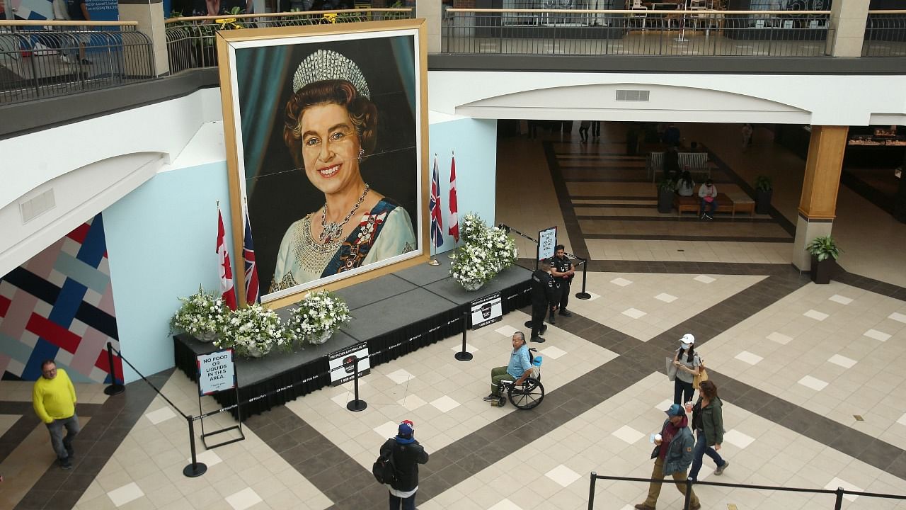 Shoppers walk past a five-meter-high image of Queen Elizabeth II. Credit: Reuters Photo