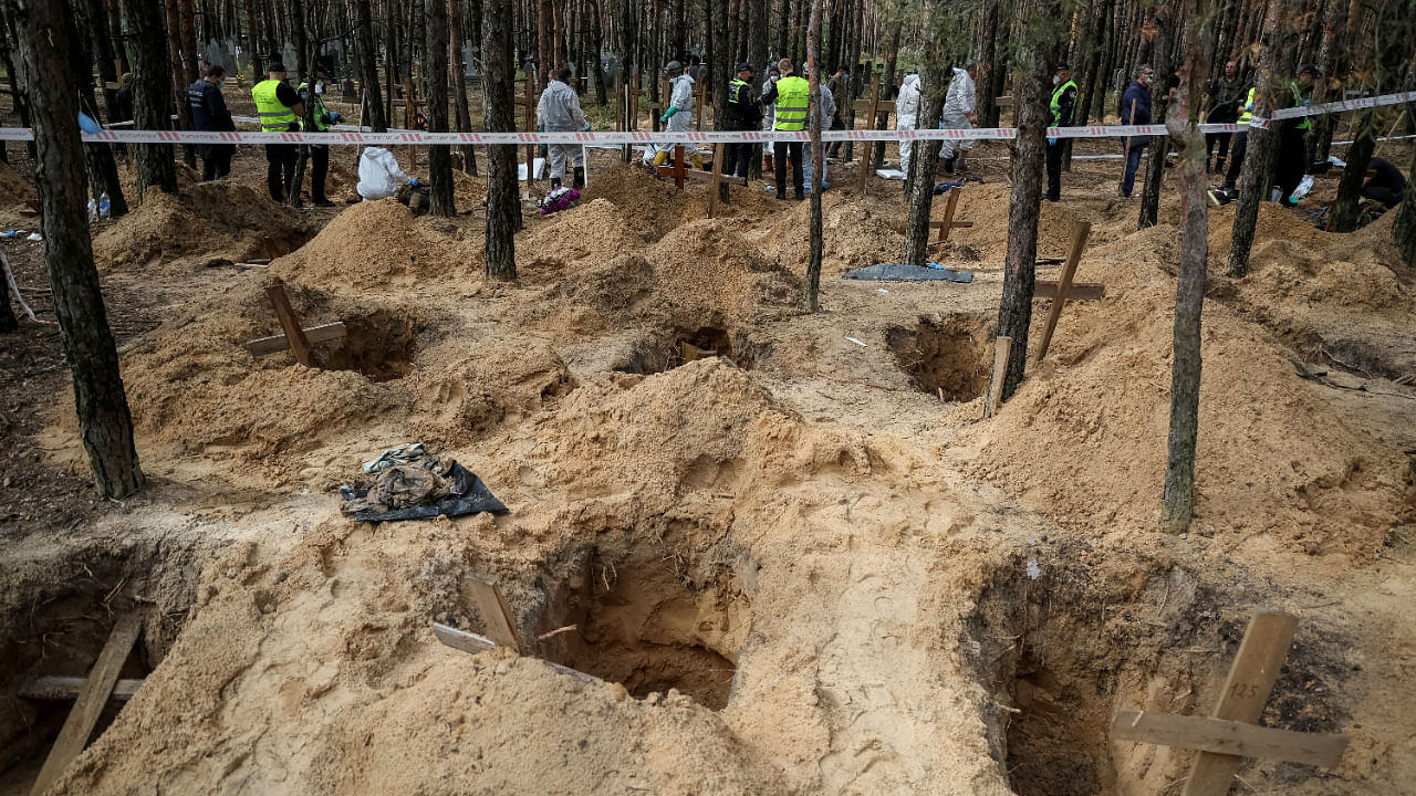 Police and experts work at a place of mass burial during an exhumation, as Russia's attack on Ukraine continues, in the town of Izium, September 17, 2022. Credit: Reuters Photo
