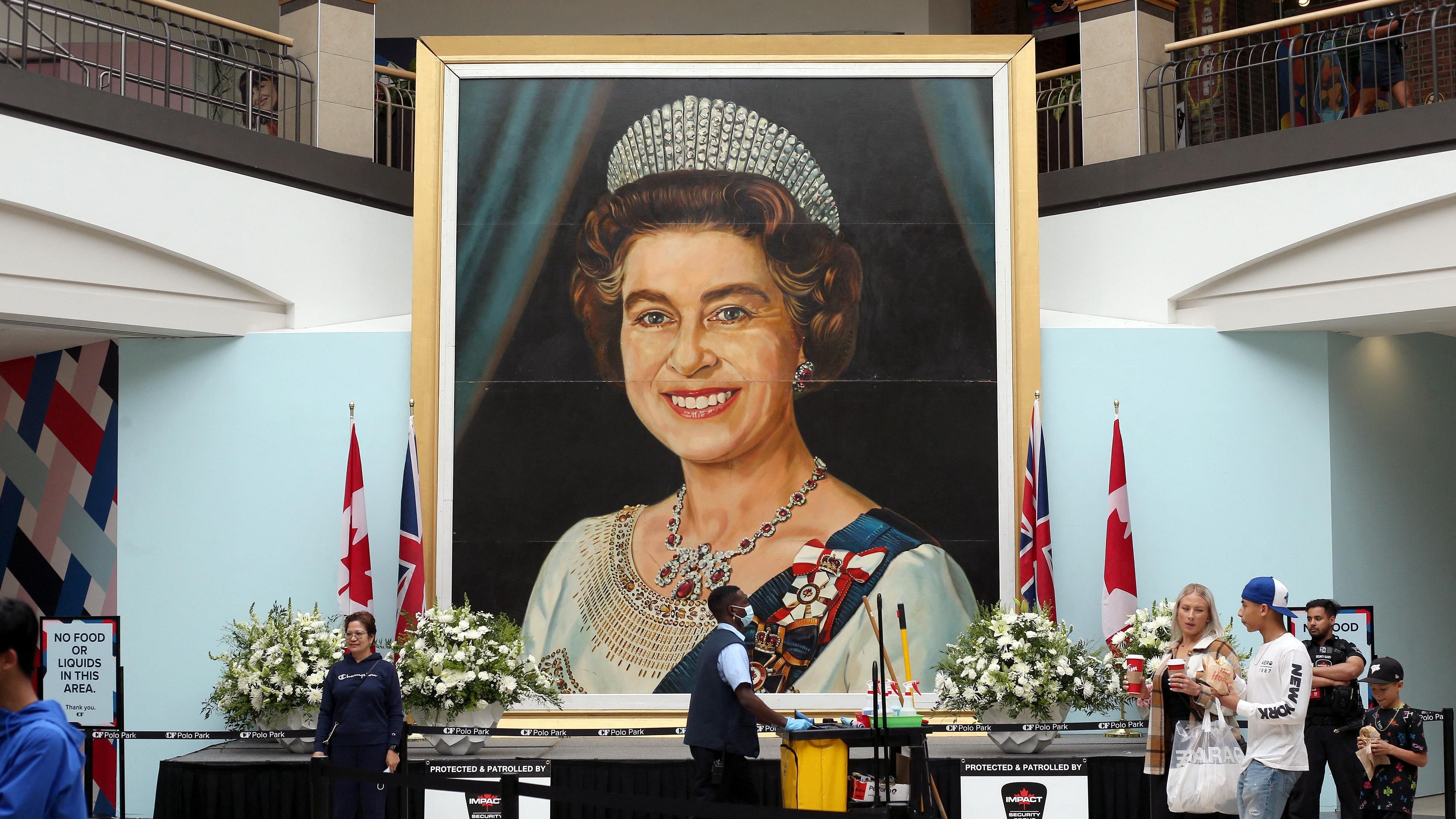 Shoppers walk past a five-meter-high image of Queen Elizabeth II, painted by billboard artist Gilbert Burch in 1979. Credit: Reuters Photo